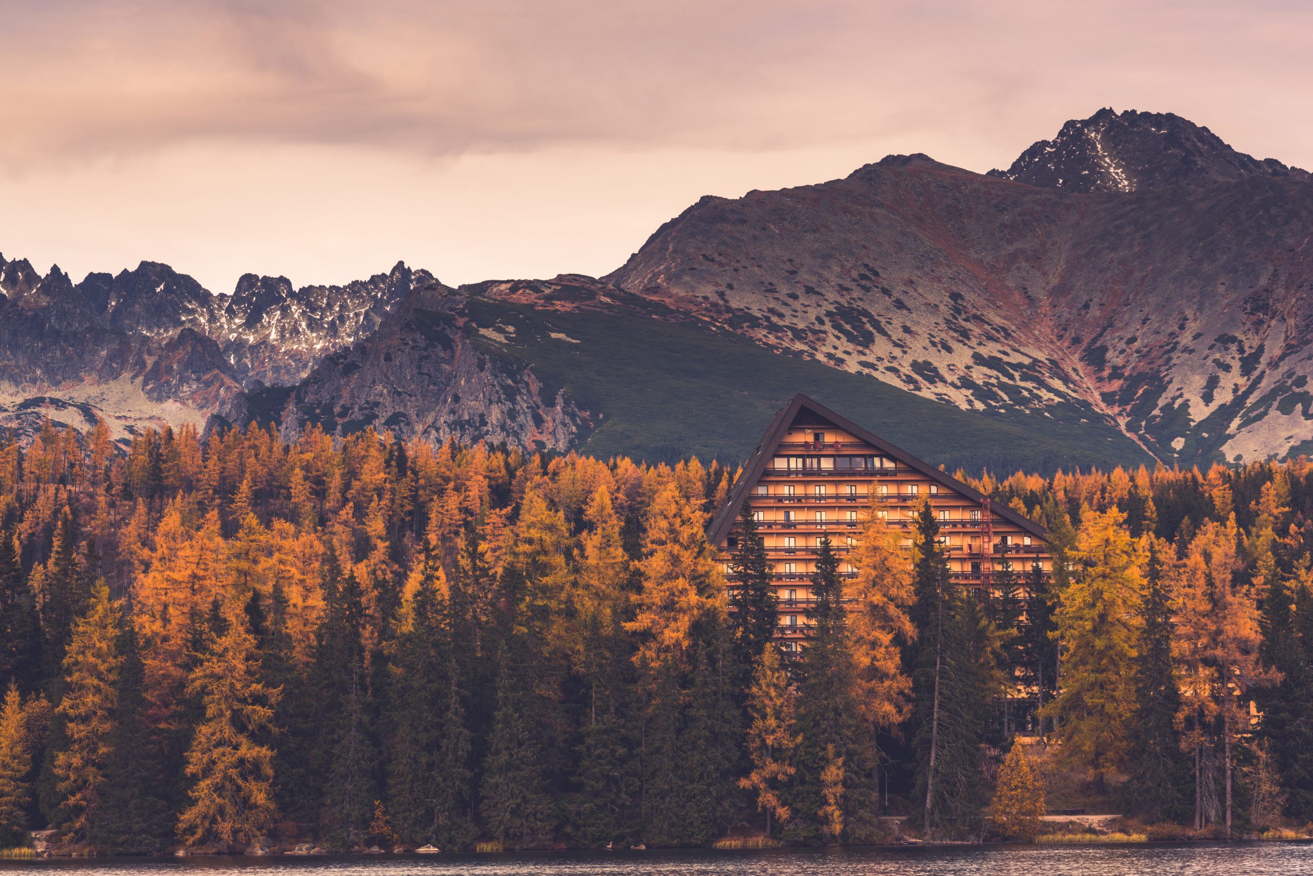autumn colors on forest over lake in high mountains